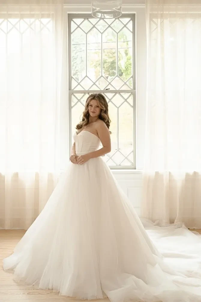 Model is wearing a strapless ball gown wedding dress with boning on the bodice