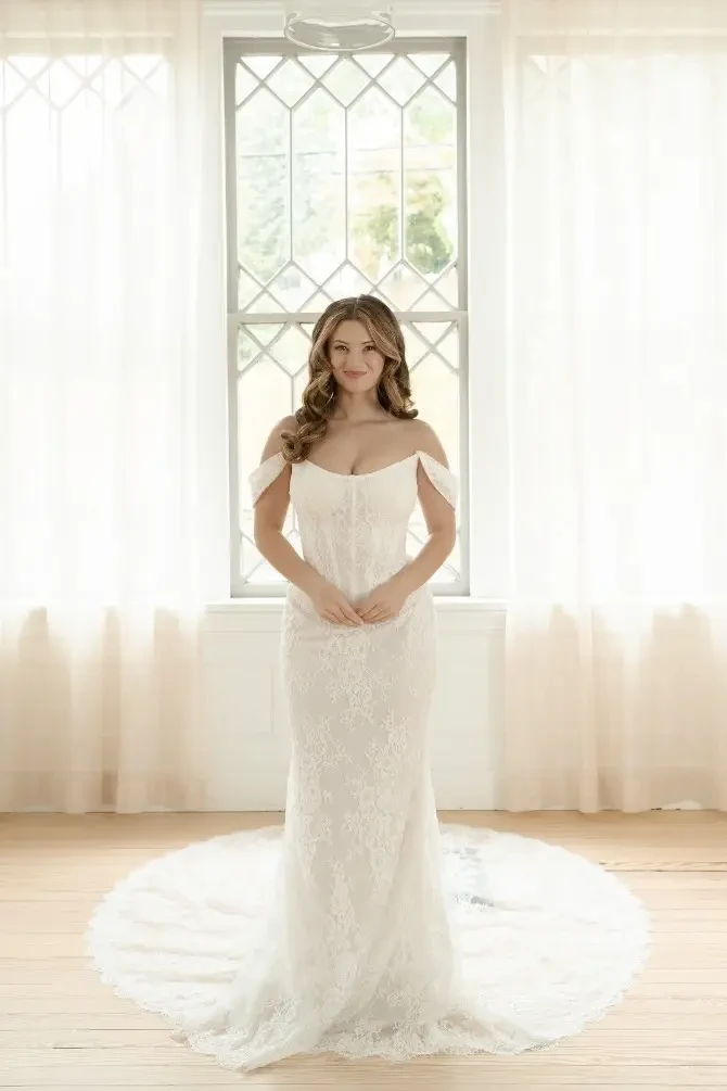 Model is wearing an off the shoulder wedding dress with a corset bodice 