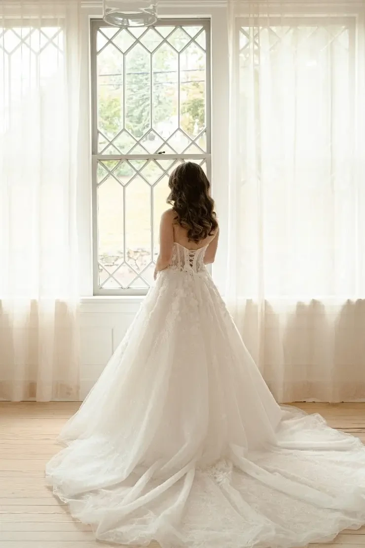 Model is wearing a tulle strapless bridal gown with 3d floral appliques 