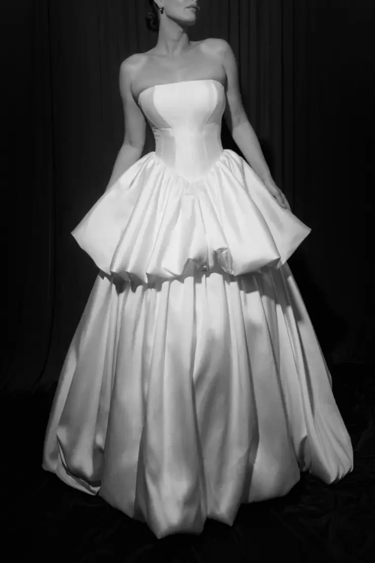 model is wearing a strapless wedding gown with a tiered full skirt