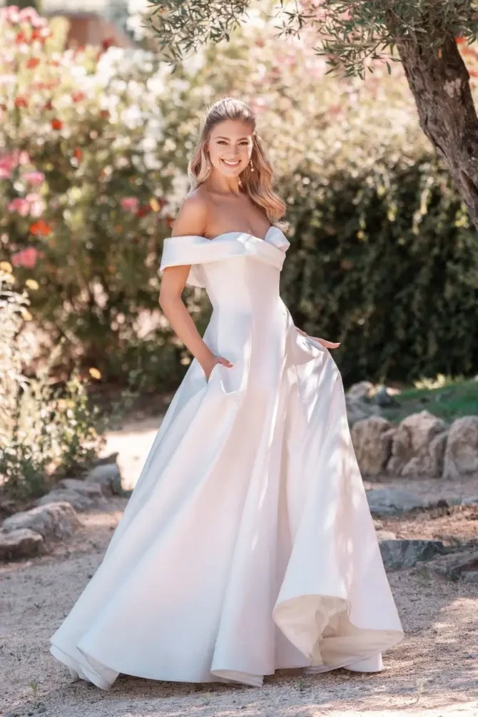 model is wearing an off the shoulder a-line wedding dress