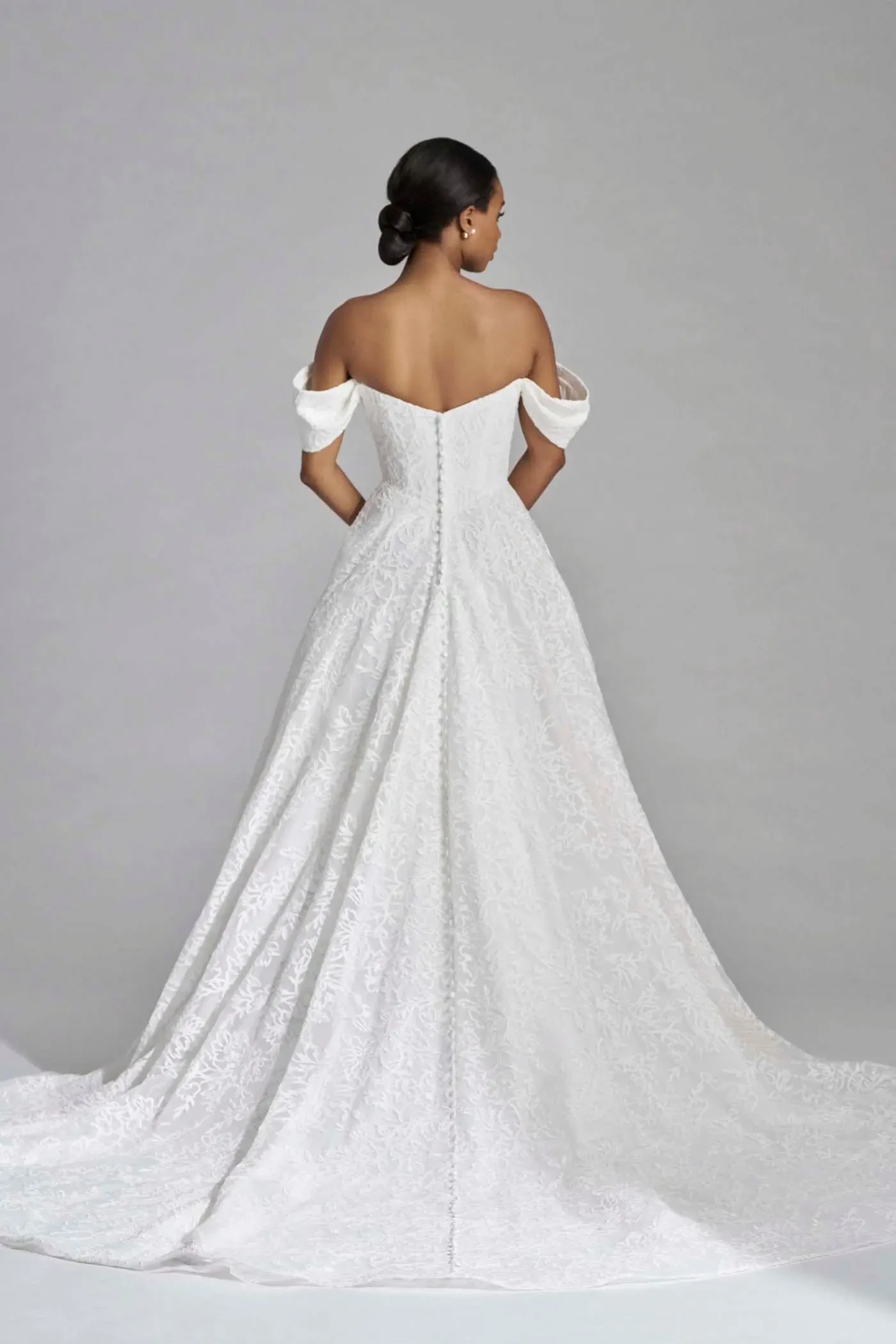 model is wearing an a-line off the shoulder wedding dress