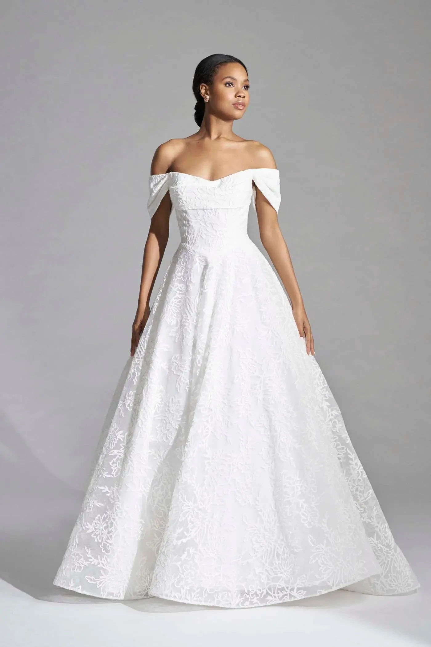 model is wearing an a-line off the shoulder wedding dress
