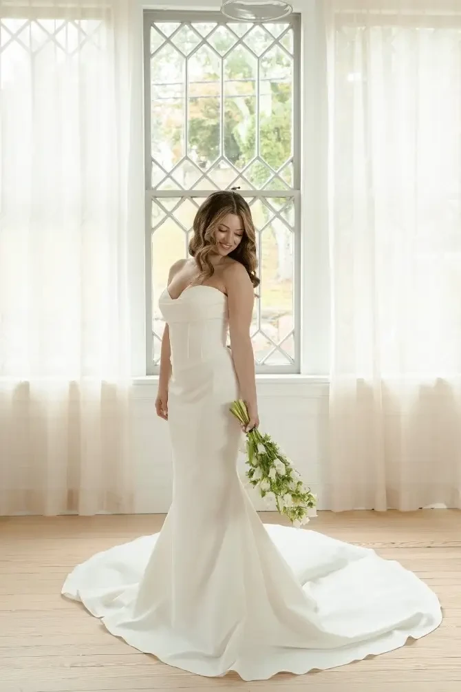 Model is wearing a strapless fit and flare minimalist wedding gown with a sweetheart neckline